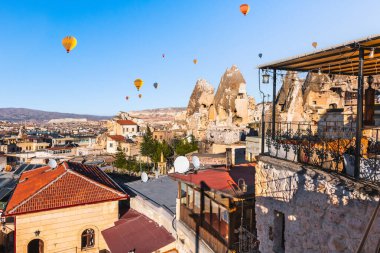 Güneş doğarken Goreme kasabası, Kapadokya, Türkiye. Şehrin üzerinde mavi gökyüzünde uçan sıcak hava balonları ve kaya oluşumları. Meşhur seyahat yeri.