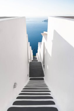 Santorini Adası, Yunanistan 'da beyaz mimari. Denize giden merdivenler. Mavi deniz ve mavi gökyüzü gün batımında. Seyahat ve tatil kavramı
