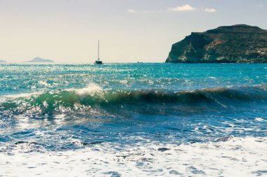 Yunanistan 'ın Santorini adasındaki kırmızı plaj. Yatlar kıyıya yakın seyrediyor. Güneşli bir günde yaz deniz manzarası