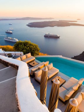 Yunanistan 'ın Santorini adasında güzel bir gün batımı. Deniz manzaralı lüks yüzme havuzu. Seyahat ve yaz tatili konsepti