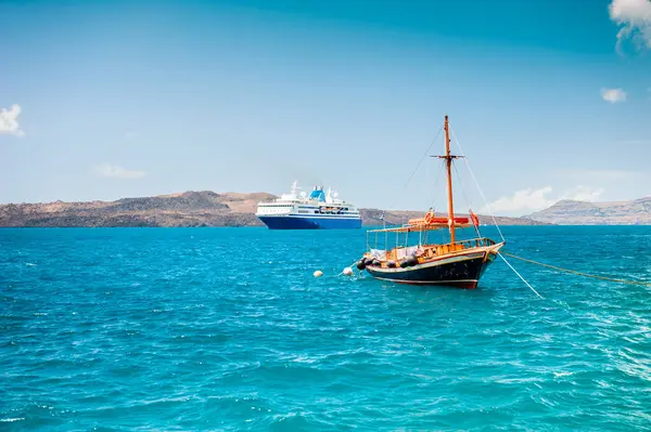 Santorini Adası, Yunanistan. Gemi turu ve kıyıya yakın ahşap bir tekne. Mavi deniz ve güneşli bir günde mavi gökyüzü. Seyahat ve tatil kavramı