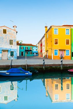 Burano Adası, Venedik, İtalya 'da renkli bir mimari. Kanalda mavi panjurlu ve mavi botlu sarı ev..