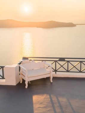 Yunanistan 'ın Santorini adasında güzel bir gün batımı. Terasta deniz manzaralı sandalye. Seyahat ve yaz tatili konsepti