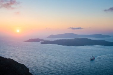 Yunanistan 'ın Santorini adasında pembe sisli gün batımı. Deniz ve adaların manzarası. Güzel yaz deniz manzarası.