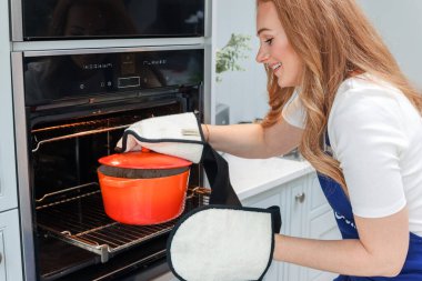 Genç bayan mutfakta hazırlanıyor. Sağlıklı yiyecekler. Salata. Diyet olsun. Diyet Konsepti. Sağlıklı yaşam tarzı. Evde yemek pişirmek. Yemek hazırlayın. Fırın eldivenleriyle tencereyi fırından çıkarıyorum.