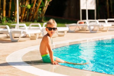 Küçük mutlu çocuk tatil köyündeki havuzda eğleniyor. Çocuklar için yaz tatili