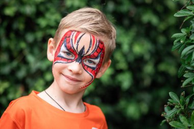 Cute little boy with face paint. Face painting, kid painting face at the birthday party or on holidays