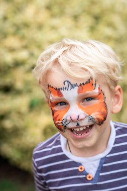 Cute little boy with face paint. Face painting, kid painting face at the birthday party or on holidays