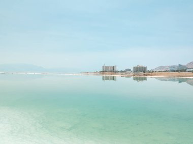 Ölü Deniz tuz kristalleri oluşumlarındaki manzara manzarası, İsrail 'in Ein Bokek plajındaki berrak yeşil sakin su