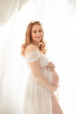 Güzel kızıl saçlı orta yaşlı hamile bir kadın evde bebek bekliyor.