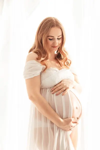 自宅で赤ちゃんを期待する美しい赤毛中年の妊婦 ストックフォト