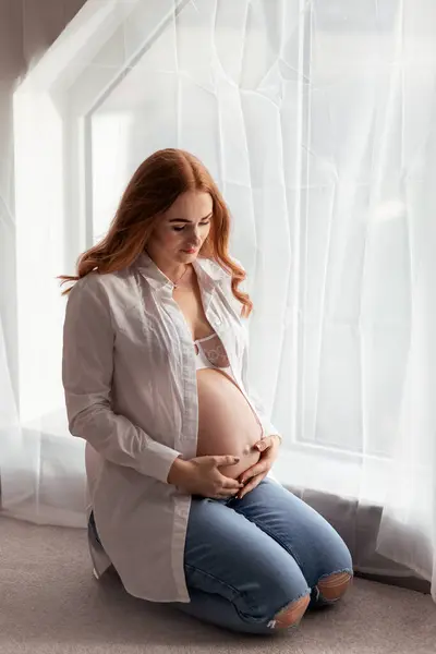 自宅で赤ちゃんを期待する美しい赤毛中年の妊婦 ロイヤリティフリーのストック写真
