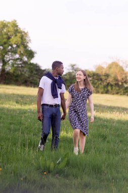 Genç bir çift, açık havada yaz gününün tadını çıkarıyor. Siyah bir adam ve beyaz bir kadın, doğal bir bahçe bahçesinde birlikte. Romantizm, sevgi ve çeşitliliği barışçıl, güneşli bir ortamda ifade ediyorlar.