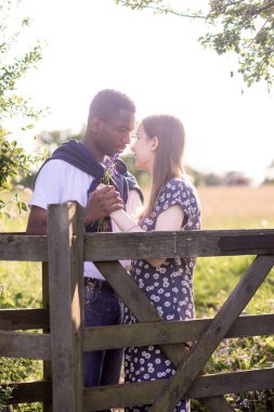 Genç bir çift, açık havada yaz gününün tadını çıkarıyor. Siyah bir adam ve beyaz bir kadın, doğal bir bahçe bahçesinde birlikte. Romantizm, sevgi ve çeşitliliği barışçıl, güneşli bir ortamda ifade ediyorlar.