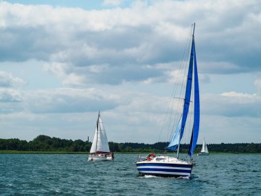 Mavi yelkenli yelkenli Rüzgarlı bir yaz gününde bir gölde yelken açıyor