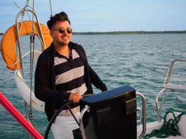 Yakışıklı, siyah saçlı, direksiyonlu, yelkenli, ya da tatilde yelkenli.