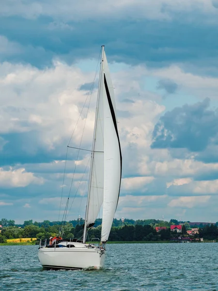 sailing yacht or sailboat on full sails swims on a lake in a windy day