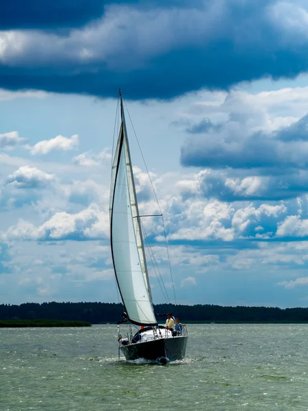 one sailing yacht sailing at full sail on a lake