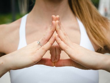 Yoga yapan ve elleriyle yoga yapan genç bir kadın.