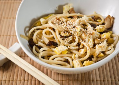 Mantarla pişirilmiş sebzeli udon eriştesi ve susam tohumuyla süslenmiş soya soslu omlet.