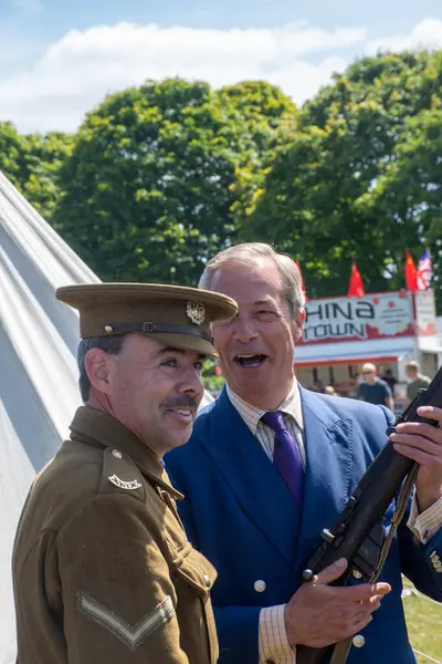 stock image COLCHESTER ENGLAND June 29 2024: Nigel Farage with world war I gun and re-enactment entusiast