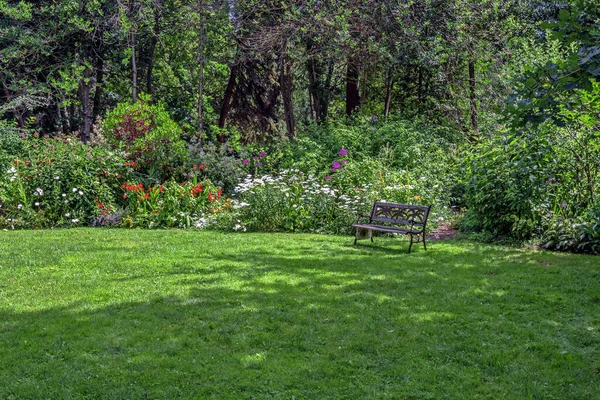 リッチモンド市のポーリック近隣公園に休憩所 開花低木の間の花壇と緑の芝生の上の木の天蓋の下のベンチ ブリティッシュコロンビア州 カナダ — ストック写真