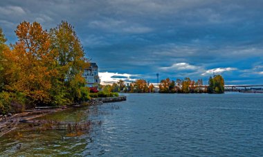 Fraser Nehri 'nin kıyısında güzel bir yerde ikamet yeri, binaların önünde park alanı, sonbahar renklerine boyanmış ağaçlar, bulutlu gökyüzü.