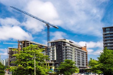 Richmond City 'de yüksek binaların inşaatı, endüstriyel inşaat alanı, inşaat ekipmanları, mavi bulutlu bir gökyüzünün arka planında birkaç inşaat vinci.