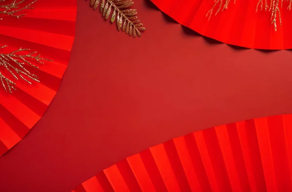 赤の背景に紙のファンと黄金の小枝 コピースペース付きシンボル中国の新年のトップビュー ストック画像