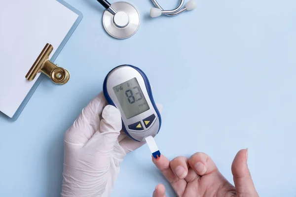 患者の血糖値を確認する手袋をしている医者の手と血糖値計 ストック画像
