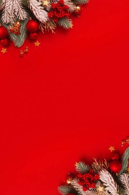 Kırmızı zemin üzerinde noel süsü ve çam ağacı var. Yeni yıl tebrik kartı. Dikey biçim.