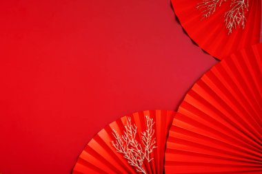 Kağıt hayranları Çin 'in yeni yıl manzarasını fotokopi alanıyla sembolize ediyor. Tek renkli kırmızı arkaplan.