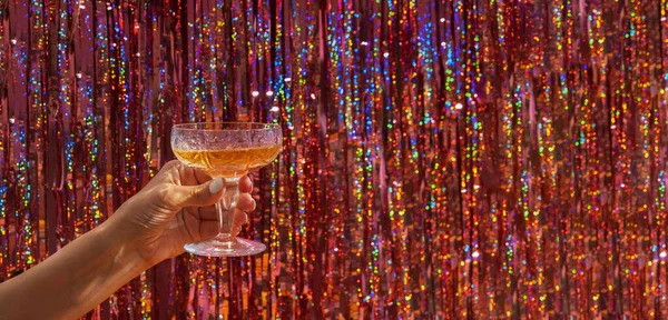 A glass of champagne in a womans hand on the background of a festive New Years night party background.