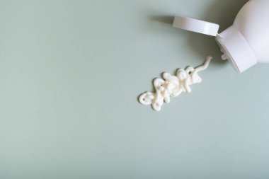 Pastel yeşil arka plan görünümlü beyaz kozmetik leke ve şişe.