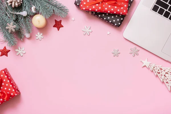 Christmas New Year decoration on work table with laptop, copy space, top view, flat lay on pink background.
