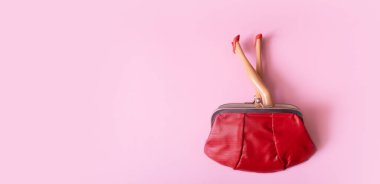 Kırmızı ayakkabılı bebek bacakları cüzdanın üst görüntüsünden dışarı sarkmış. Yaratıcı kadın alışverişi veya finans konsepti.