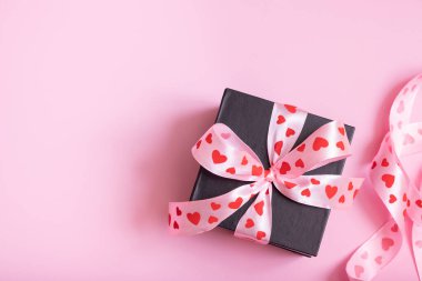 Kalpleri pembe arka planda olan hediye kutusu. Sevgililer Günü hediyesi düzdü. Boşluğu kopyala