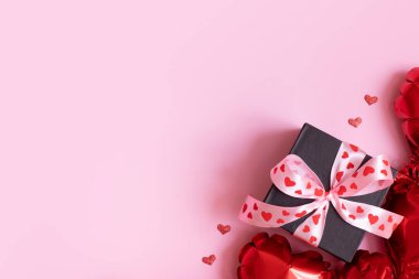 Pembe arka planda yay ve kalp şeklinde balonlar olan hediye kutusu. Düz Sevgililer Günü arkaplanı kopyalama alanı ile yatıyordu.