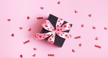 Pembe arka planda fiyonklu hediye kutusu. Sevgililer Günü hediyesi düzdü.