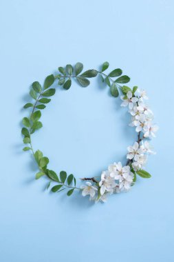 Yuvarlak çelenk çiçek çerçevesi bahar metnin için hazırlanmış. Mavi arka plan. Uzayı kopyala Dikey fotoğraf.