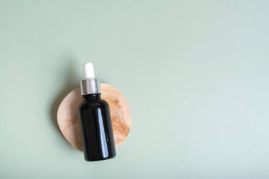 Kozmetik şişesi, pipetle ahşap kesim üst görünümü, yassı arka plan, doğa dekorasyonlu. Doğal kozmetik konsepti.