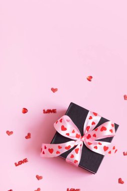 Pembe arka planda fiyonklu hediye kutusu. Sevgililer Günü hediyesi düzdü.