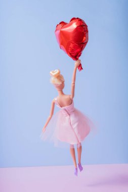 The doll is flying on a heart-shaped balloon. Valentine's Day creative concept.