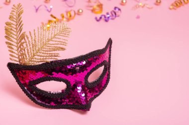 Festive face mask for masquerade or carnival celebration on pink background.