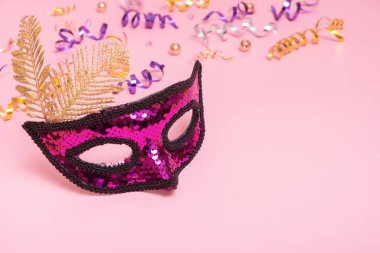 Festive face mask for masquerade or carnival celebration on colored background. Copy space.