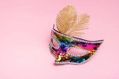 Festive face mask for carnival or masquerade celebration on colored background.