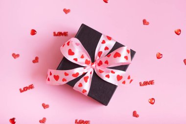 Present gift box with bow on pink background. Valentines Day greeting concept.