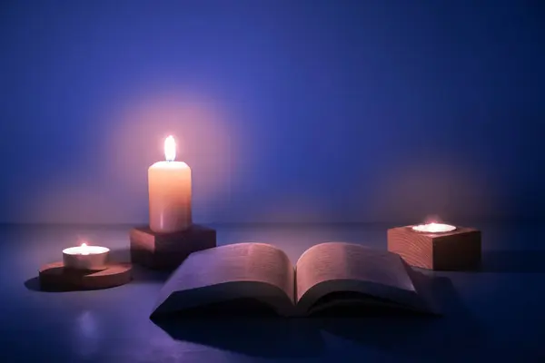 Open Christian Holy Bible Candles Lighting Dark Blue Background — 图库照片