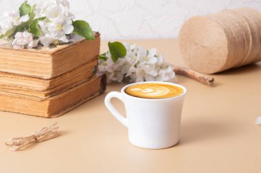 Cup of coffee and blossom apple twigs with vinage books. Springtime still life composition.