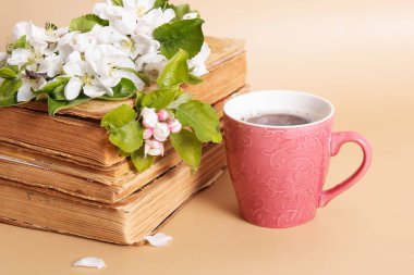 Cup of coffee and blossom apple twigs with vinage books. Springtime still life composition.
